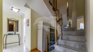 A hallway with a marble staircase, a refrigerator, and a console table.