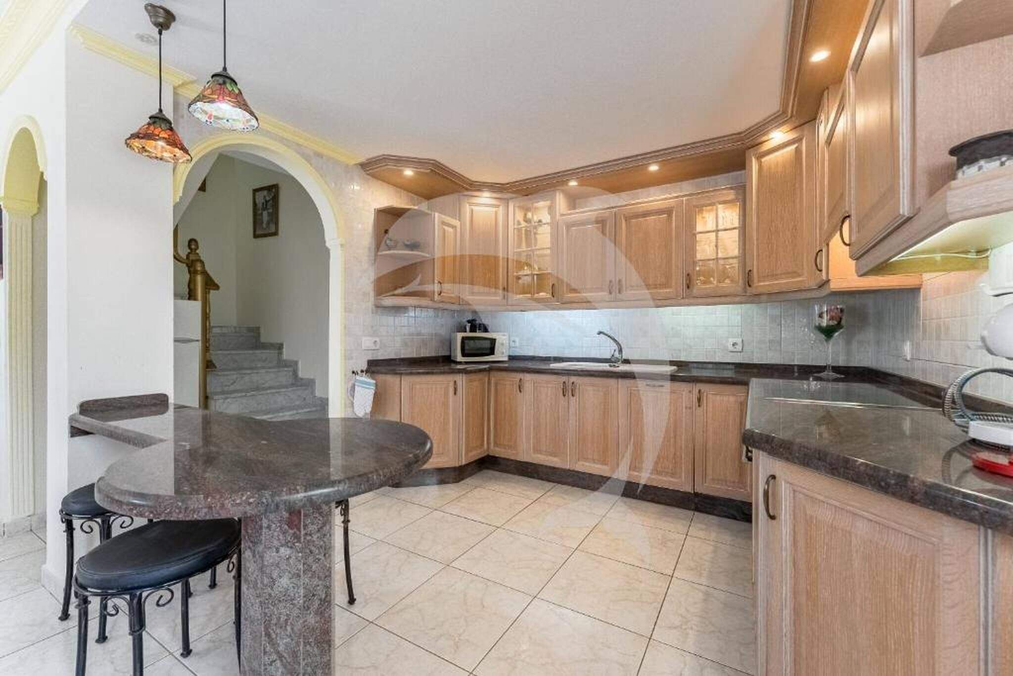 A kitchen with wooden cabinets, a granite countertop, a microwave, and a sink.