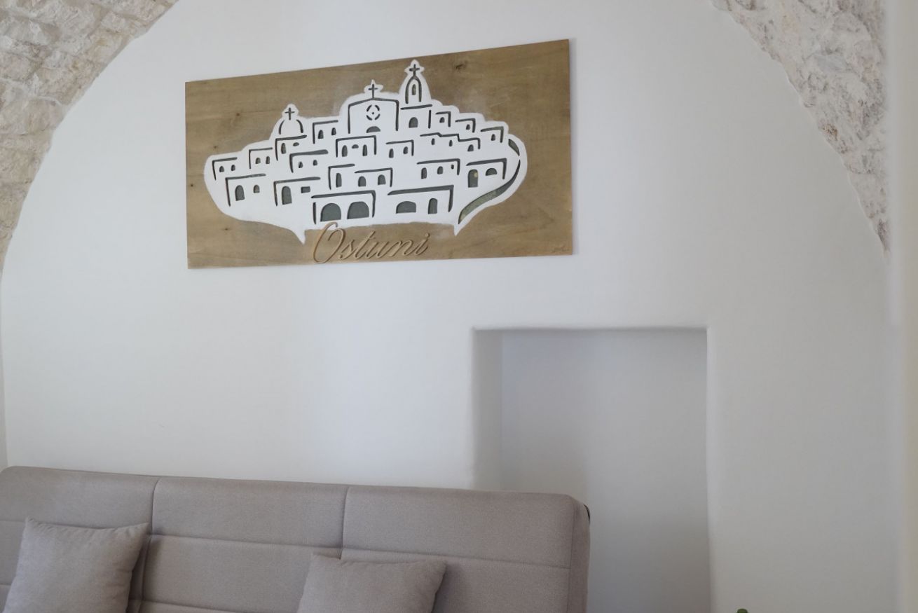 Un mur orné d’une œuvre d’art en bois représentant un paysage urbain et portant le mot « Ostuni ».