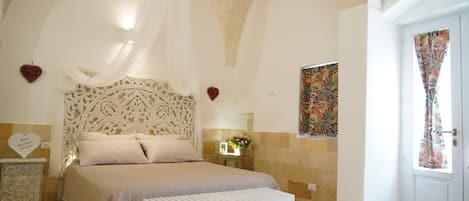 A bedroom with a bed, a bedside table, a decorative headboard, and a wall-mounted air conditioning unit.