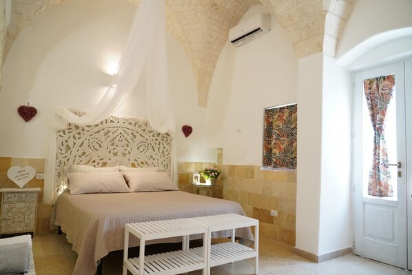 Une chambre à coucher comprenant un lit, une table de chevet, une tête de lit décorative et un climatiseur fixé au mur.