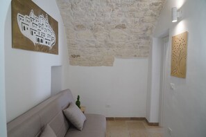 Ein Zimmer mit Steindecke, einer Couch und zwei Kunstwerken an den Wänden.