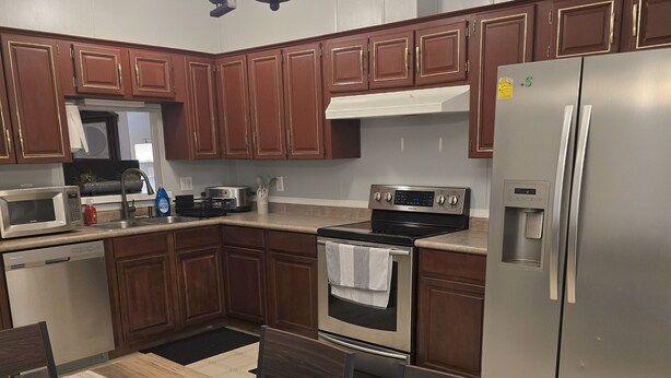 A modern kitchen with wooden cabinets, stainless steel appliances, and a dining area with a table and chairs.