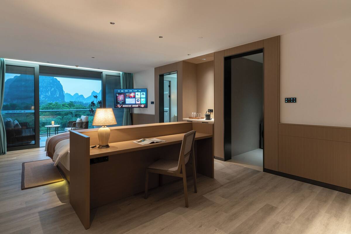 A hotel room with a desk, chair, and a TV displaying a menu.