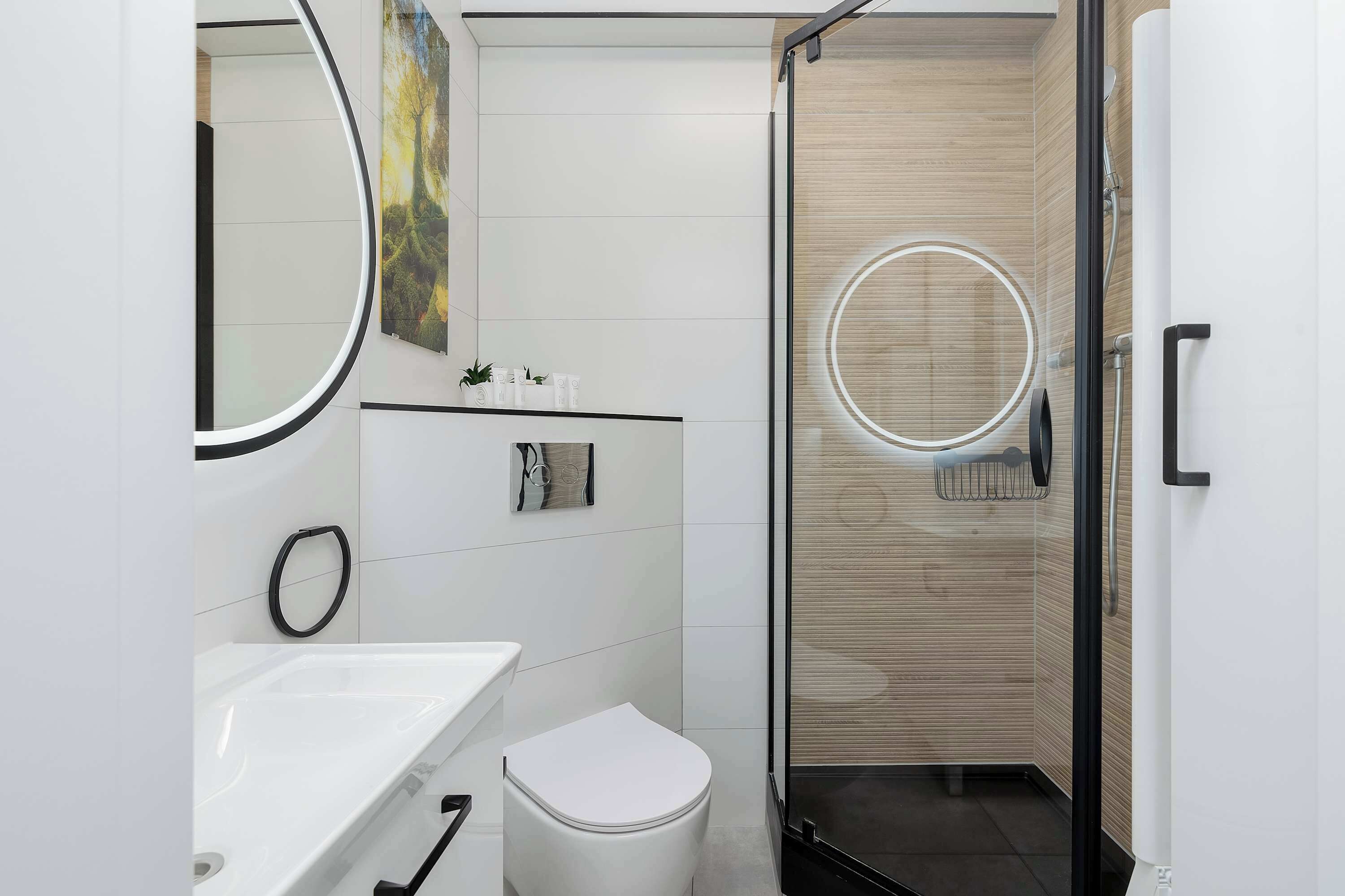 Un bagno moderno con lavandino bianco, servizi igienici e cabina doccia in vetro.