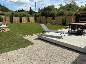 A patio area with a sun lounger, a table with chairs, and a wooden pergola.