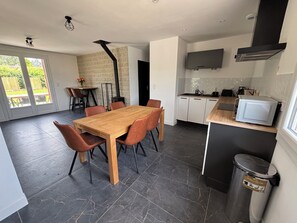 A modern kitchen with a wooden dining table and chairs, a built-in microwave, and a black range hood.