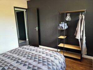 A bedroom with a bed, a wardrobe, and a built-in shoe rack.
