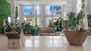 Un salon spacieux avec de grandes fenêtres, une table basse en bois et diverses plantes.