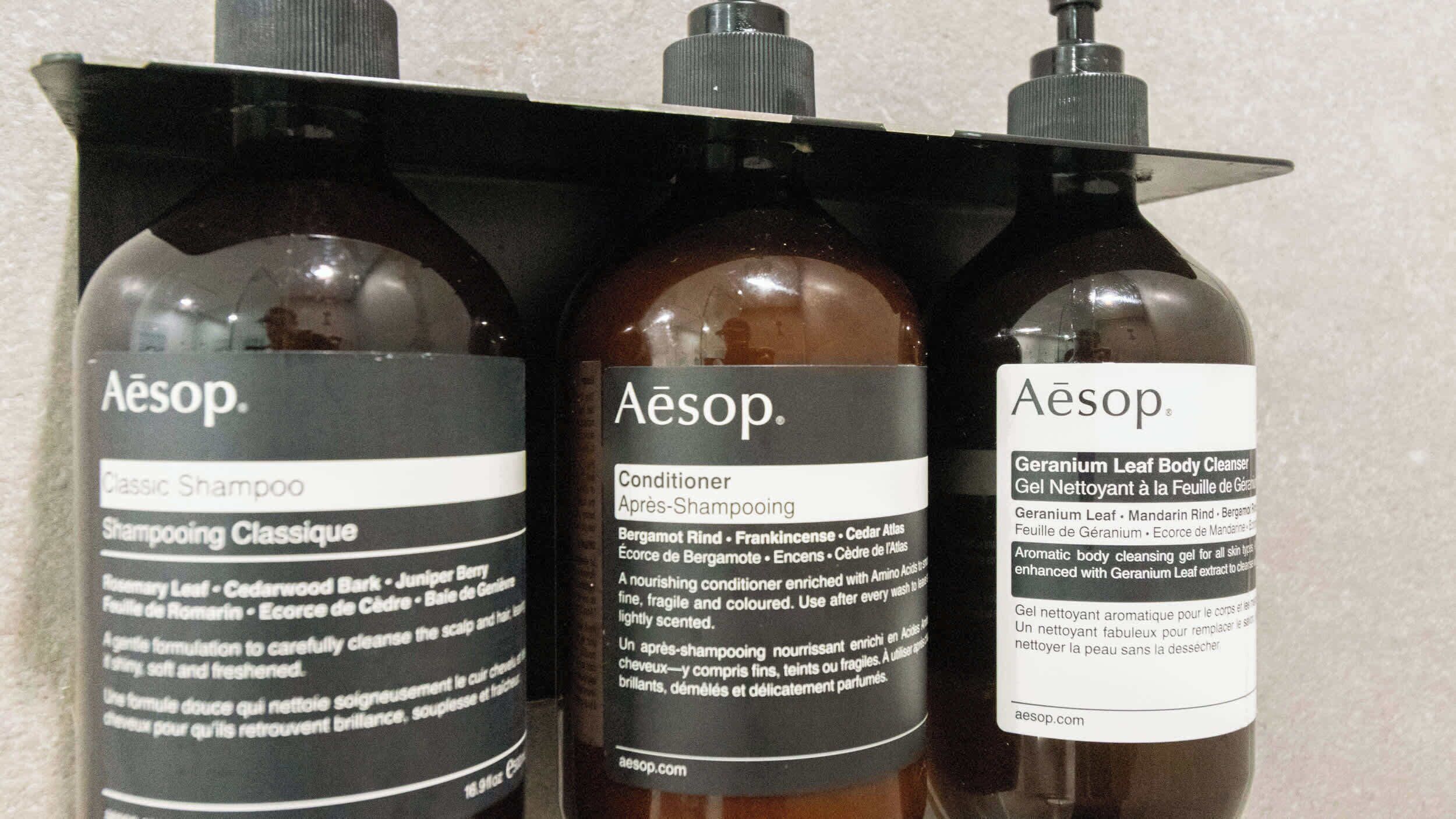 Three bottles of Aesop products: Classic Shampoo, Conditioner, and Geranium Leaf Body Cleanser.