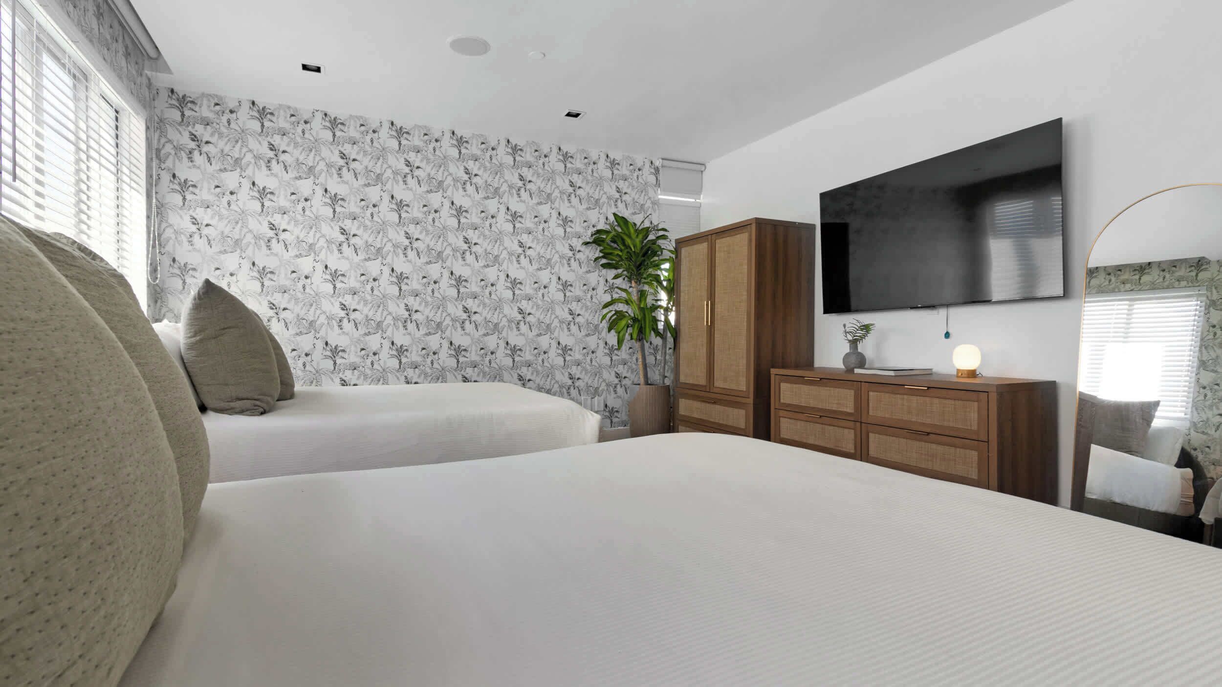 Une chambre avec deux lits, une télévision et une armoire.