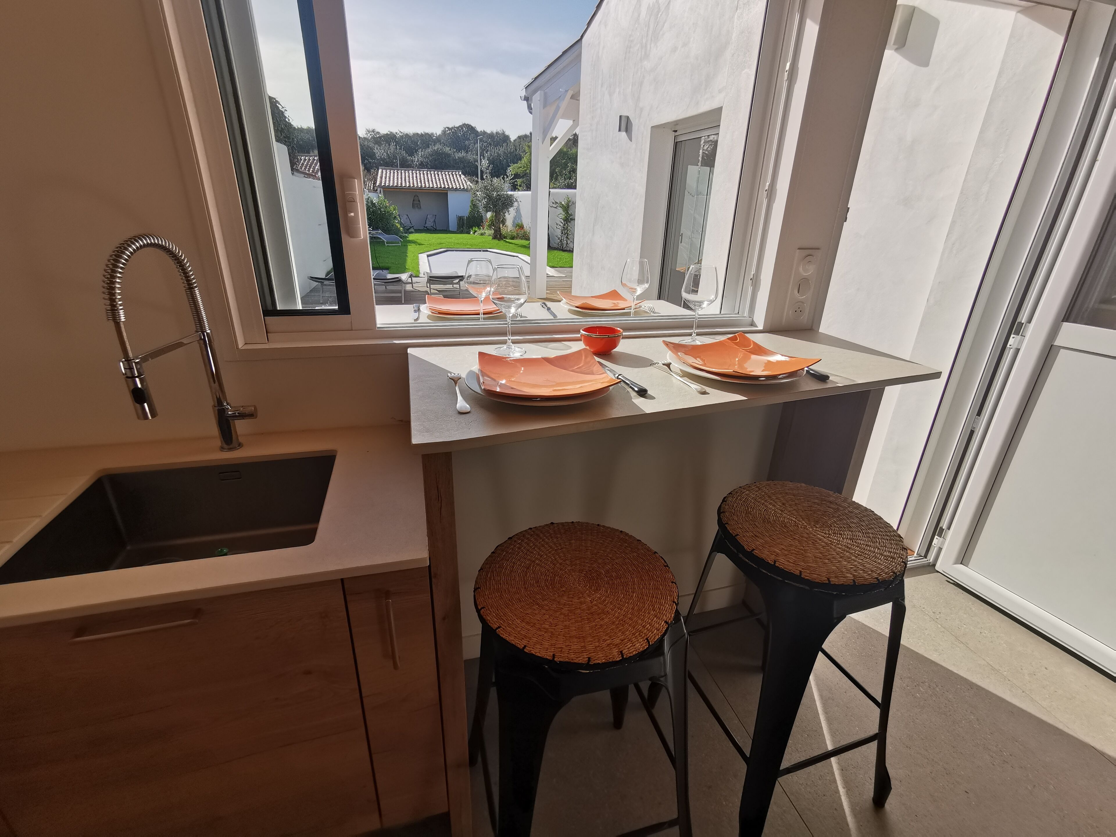 Eine moderne Küche mit Fensterblick, einer Spüle und zwei Korbstühlen.