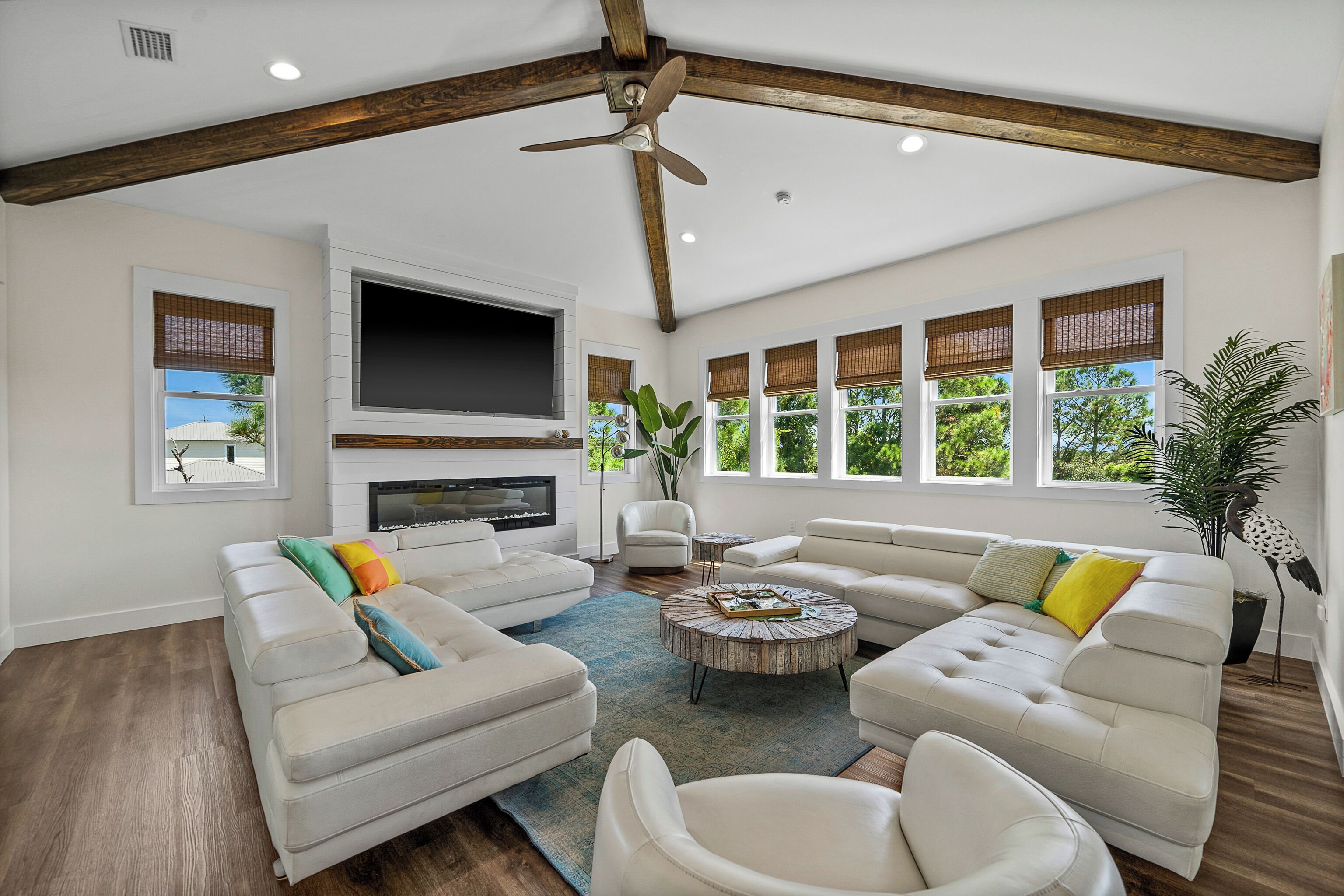 A spacious living room with a large sectional sofa, a round coffee table, and a flat-screen TV mounted on the wall.