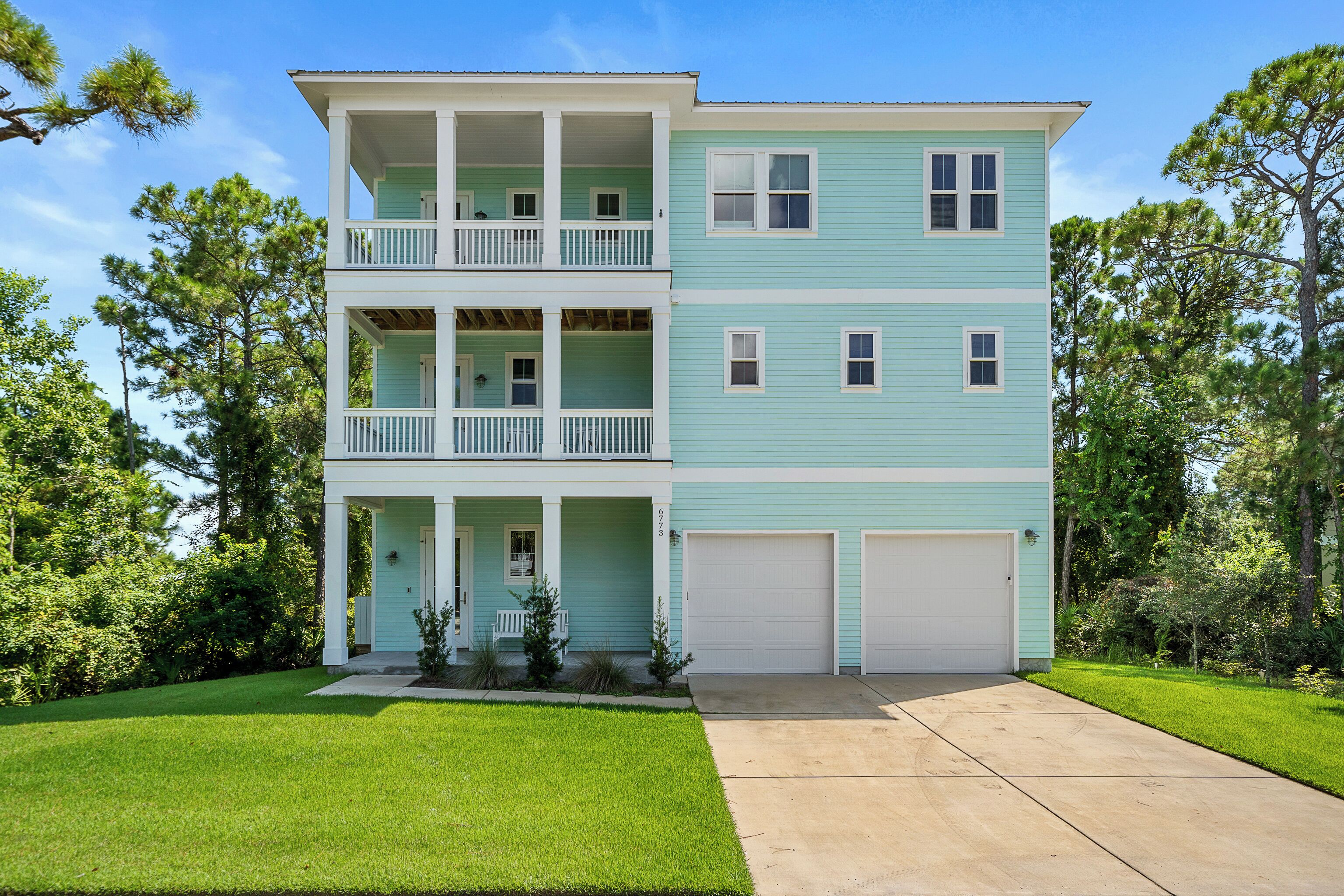 A two-story house with a front porch, a balcony on the upper floor, and a garage.