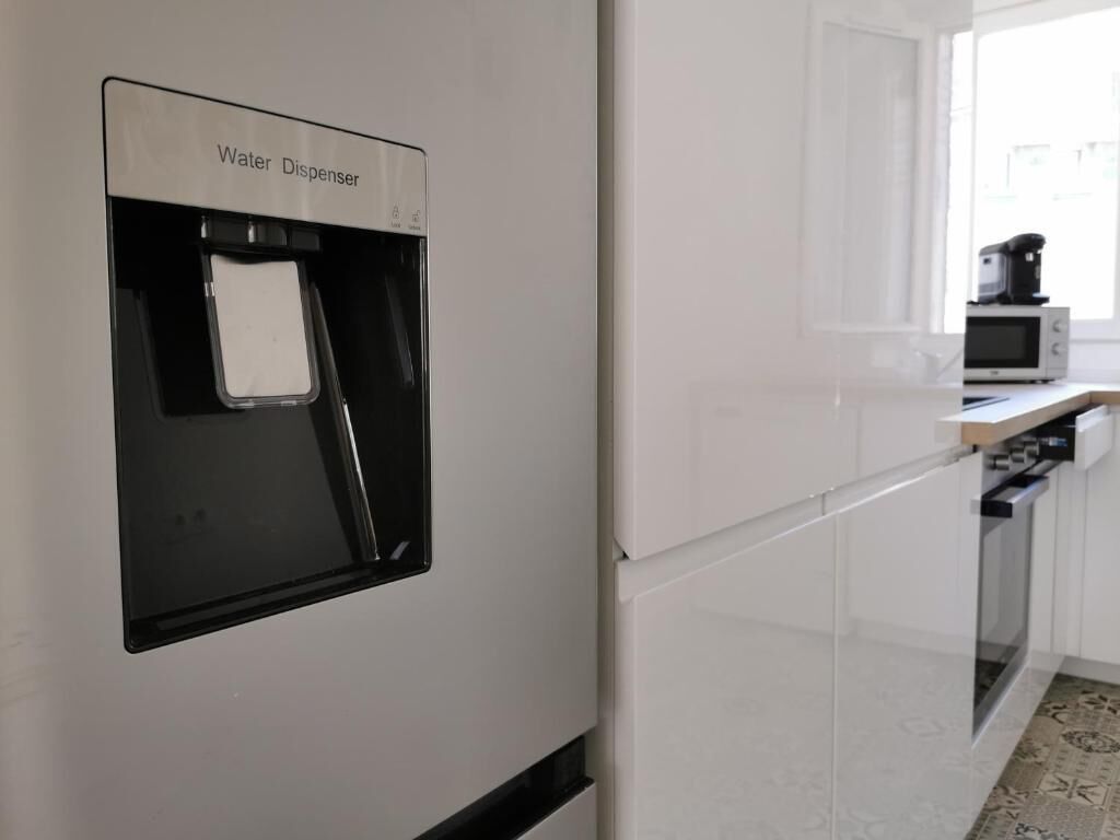 Una cocina con dispensador de agua, microondas y estufa.