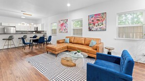 A modern living room with a sectional sofa, a coffee table, and a dining area with chairs and a table.