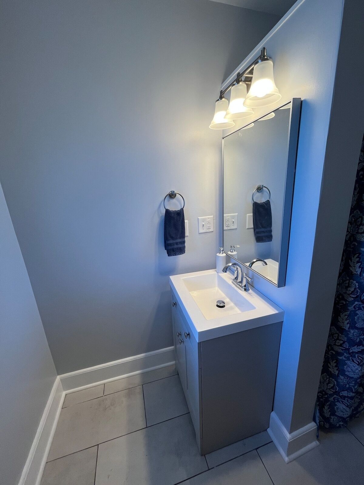 Un bany modern amb un lavabo blanc, un mirall i un escurapulides.