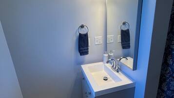 Un bany modern amb un lavabo blanc, un mirall i un escurapulides.