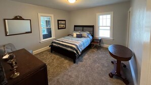 Un dormitorio con cama, mesitas de noche, cómoda y una mesa redonda.
