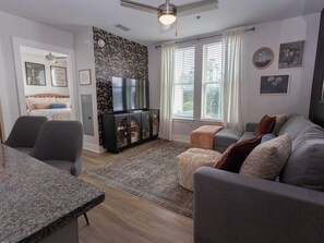 A living room with a sofa, a TV, a dining table, and a patterned rug.