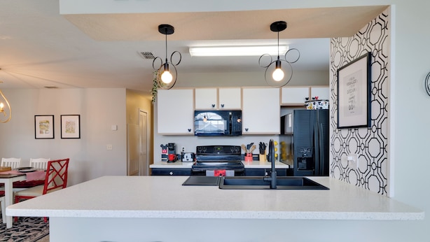 A modern kitchen with a central island, pendant lighting, and a patterned backsplash. - 5 Mi to Wdw: Resort-style Condo w/ Pool Access (Kissimmee)