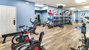Ein Fitnessraum mit Trainingsgeräten, Holzboden und blauer Wand.