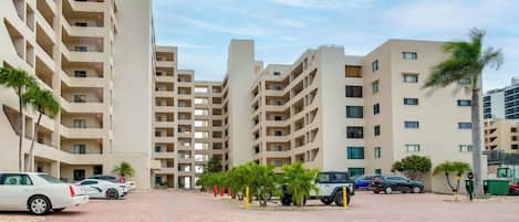 A modern apartment complex with multiple floors, a paved courtyard, and parked cars.
