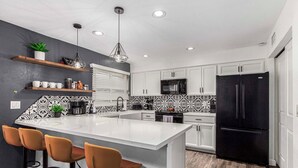 A modern kitchen with white cabinetry, a black refrigerator, and a central island with bar stools. - Walk to Old Town & Giants Stadium! Unit w/ Pool (Scottsdale)
