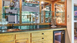 Une cuisine avec des meubles en bois, un évier en cuivre et des étagères en verre où sont exposés des objets décoratifs.