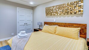 A bedroom with a wooden headboard, a large bed with yellow bedding, a white door, and a wall-mounted artwork. - Hike & Ski: Condo 8 Mi to Dtwn Salt Lake City! (Salt Lake City)