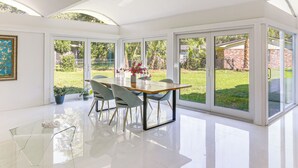 A modern kitchen with a large island, white cabinetry, and a view of the backyard through large sliding glass doors. - 2 Mi to Fsu: Unique Home w/ Patio & Spacious Yard (Tallahassee)