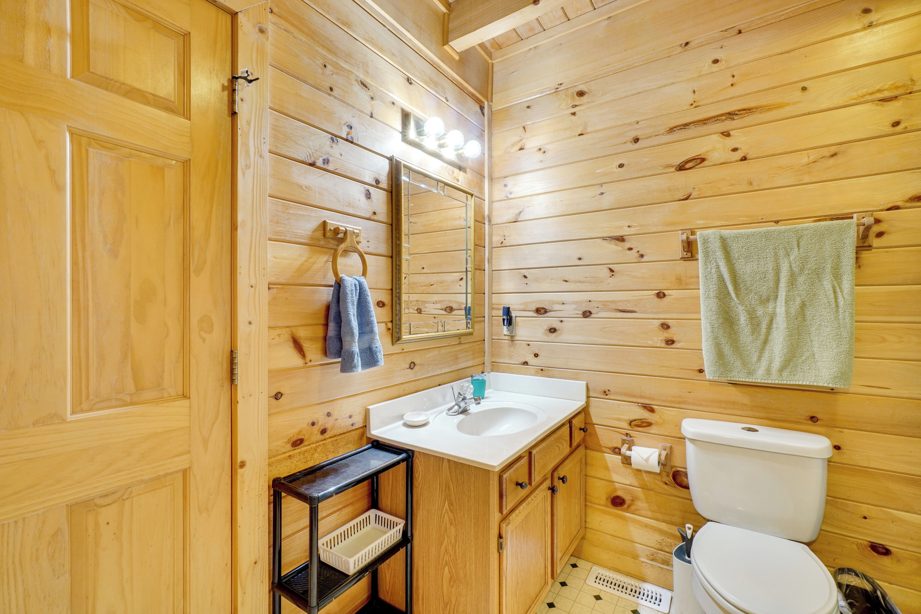A wooden cabin bathroom with a sink, mirror, and toilet.