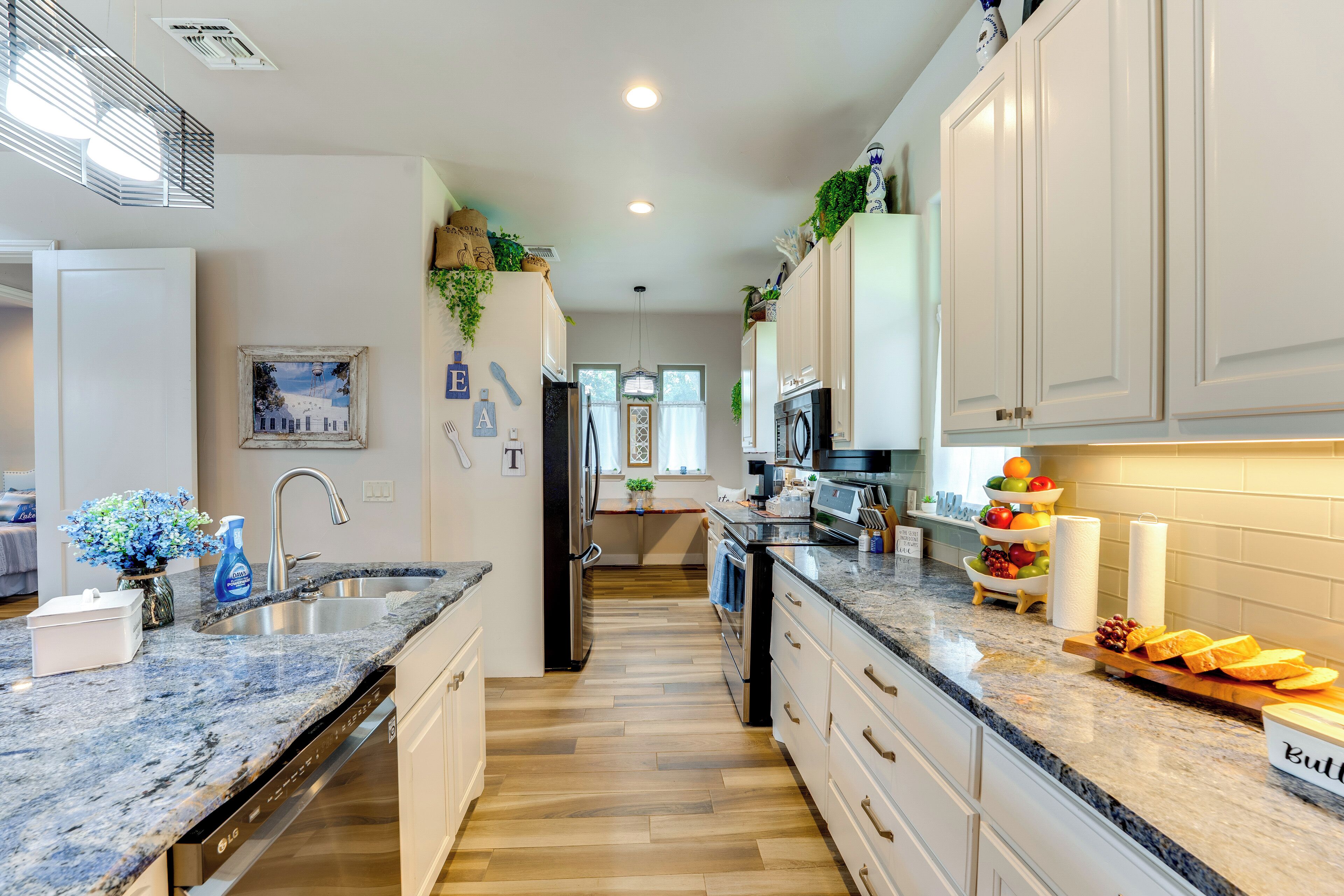 A modern kitchen with granite countertops, stainless steel appliances, and white cabinetry.