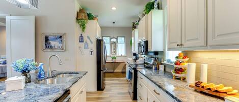 A modern kitchen with granite countertops, stainless steel appliances, and white cabinetry.