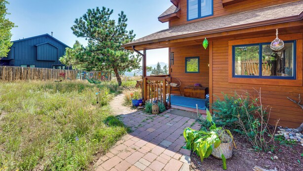 A wooden house with a covered porch, a garden with plants and a pathway leading to the entrance. - Trail Access, Hot Tub: Lakefront Boulder Retreat! (Boulder)
