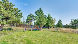 A fenced outdoor area with a grassy field, trees, and a wooden bench. - Trail Access, Hot Tub: Lakefront Boulder Retreat! (Boulder)