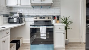 A kitchen with white cabinets, a microwave, an oven, and a potted plant. - Clean Birmingham Home Fenced Yard Bessemer (Bessemer)