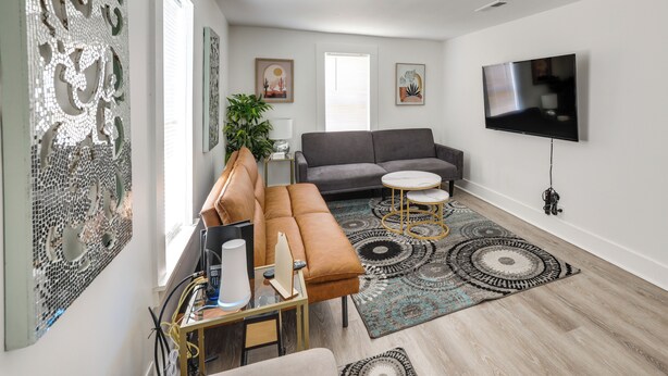A modern living room with a gray sofa, a small round table, and a TV mounted on the wall. - Clean Birmingham Home Fenced Yard Bessemer (Bessemer)
