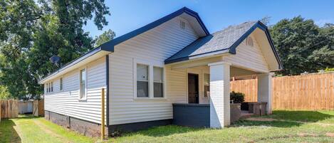 A single-story house with a front porch, a small attached garage, and a fenced backyard.
