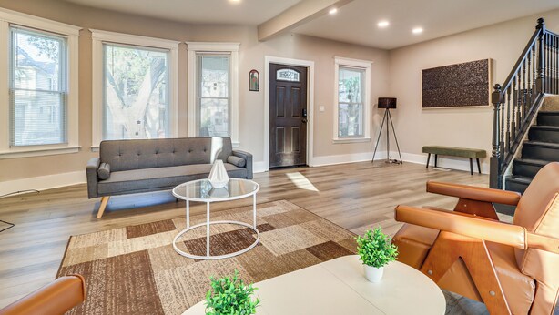 Ein geräumiges Wohnzimmer mit grauem Sofa, einem runden Couchtisch und einem braunen Ledersessel.