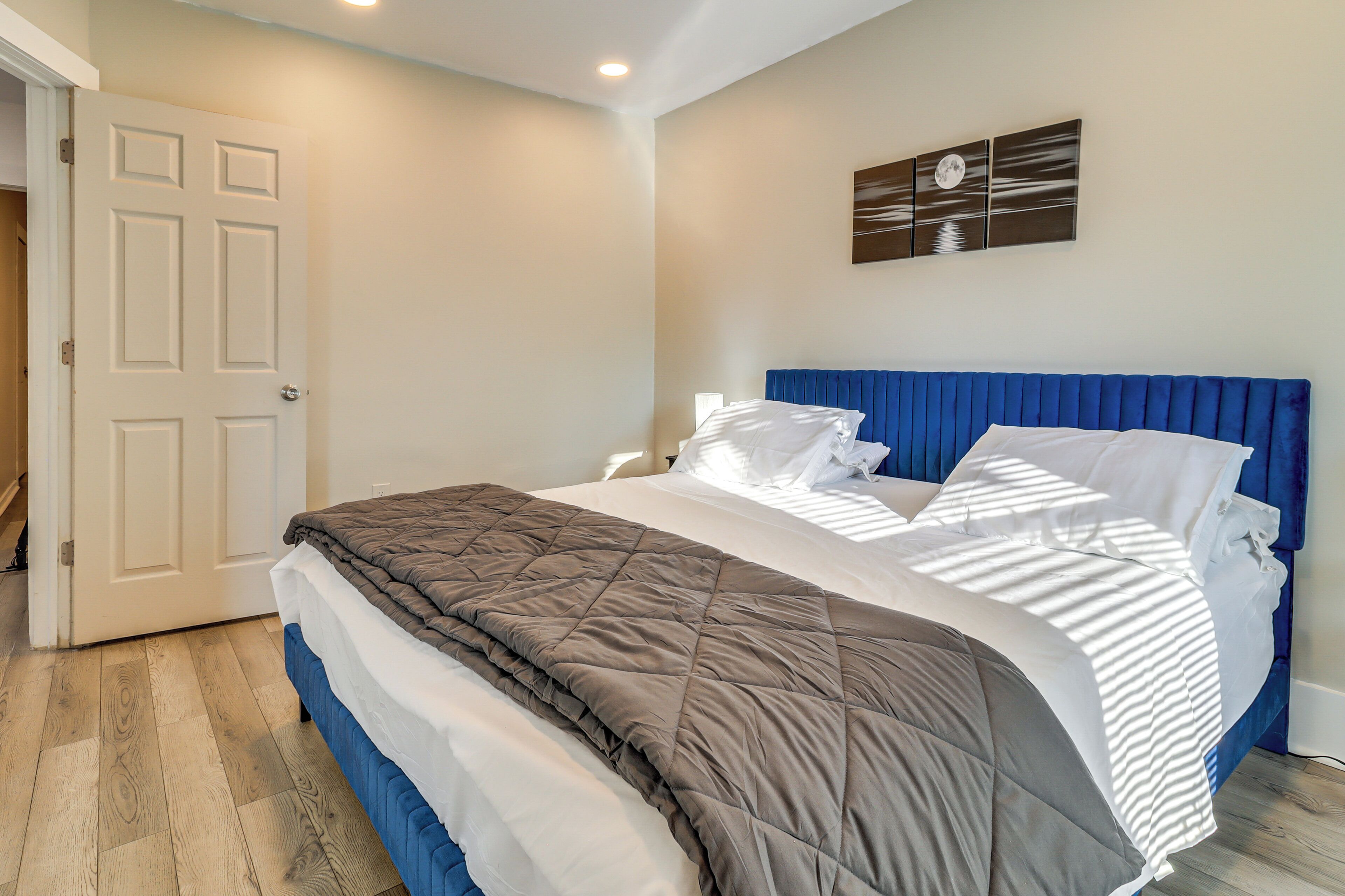 Een slaapkamer met een bed, een deur en een aan de muur hangend kunstwerk.