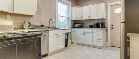 A modern kitchen with white cabinets, stainless steel appliances, and a tiled floor.