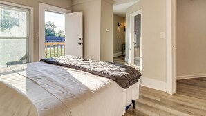 Ein Schlafzimmer mit einem Bett, einer Tür, die auf einen Balkon führt, und einem Flur.