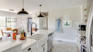 Una cocina moderna con armarios blancos, una isla grande e iluminación colgante.