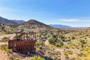 A desert landscape with a large metal structure in the foreground, a small settlement with houses in the middle ground, and mountains in the background. - Historic Retreat w/ Mtn Views in Pioche! (Pioche)