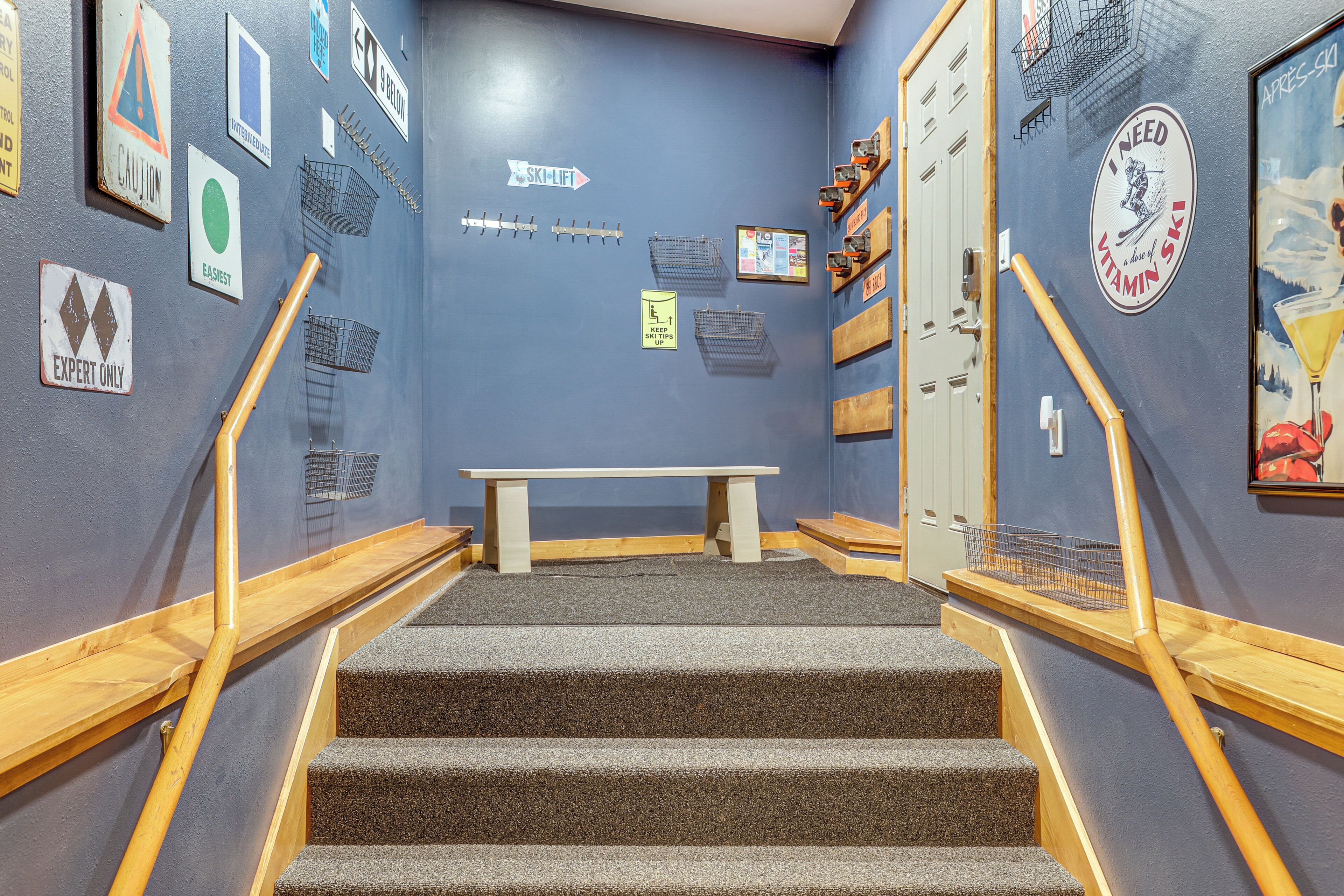 A staircase with a wooden handrail, a bench at the top, and various signs on the walls.