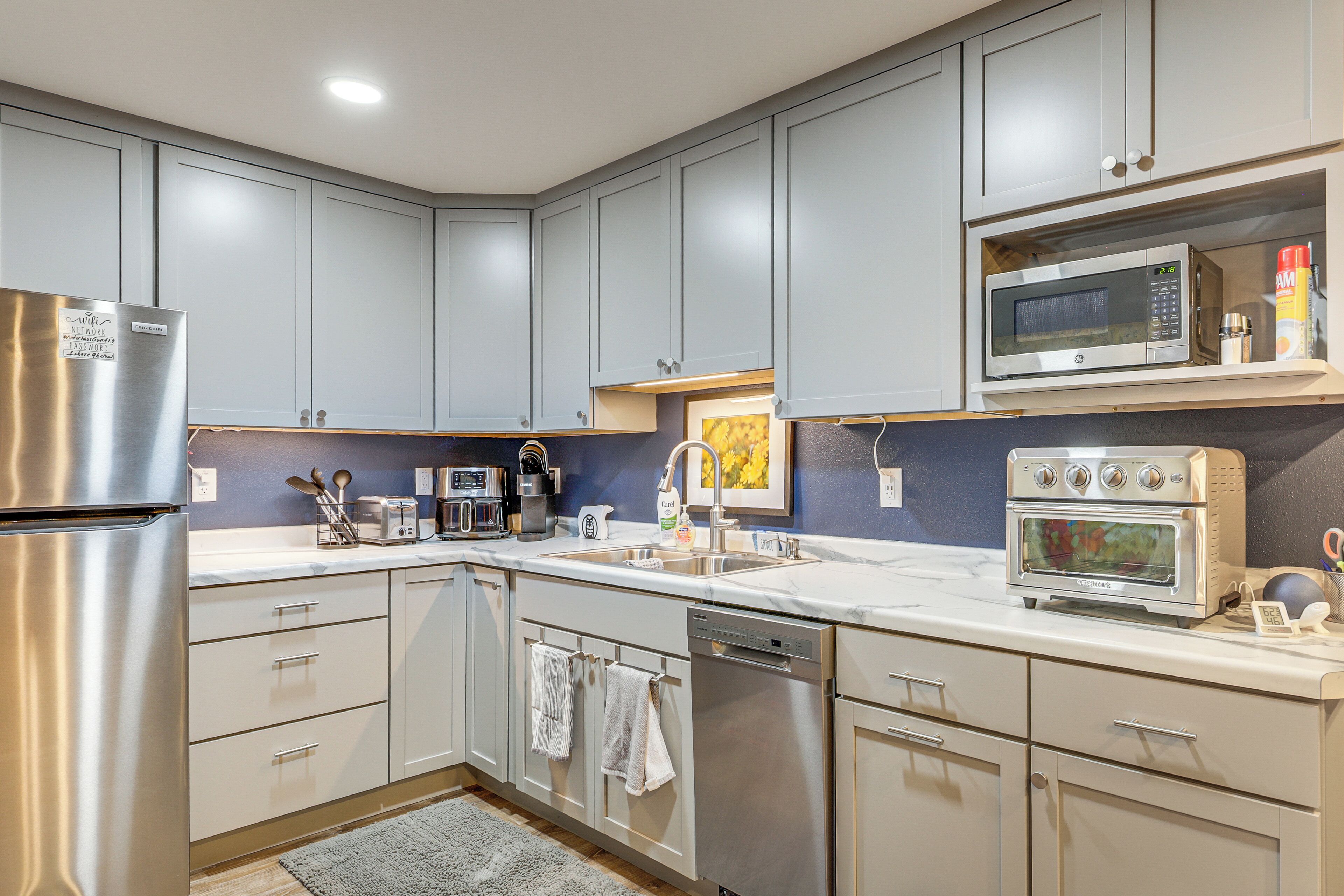 A modern kitchen with grey cabinets, stainless steel appliances, and a built-in microwave.