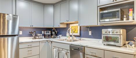 A modern kitchen with grey cabinets, stainless steel appliances, and a built-in microwave.