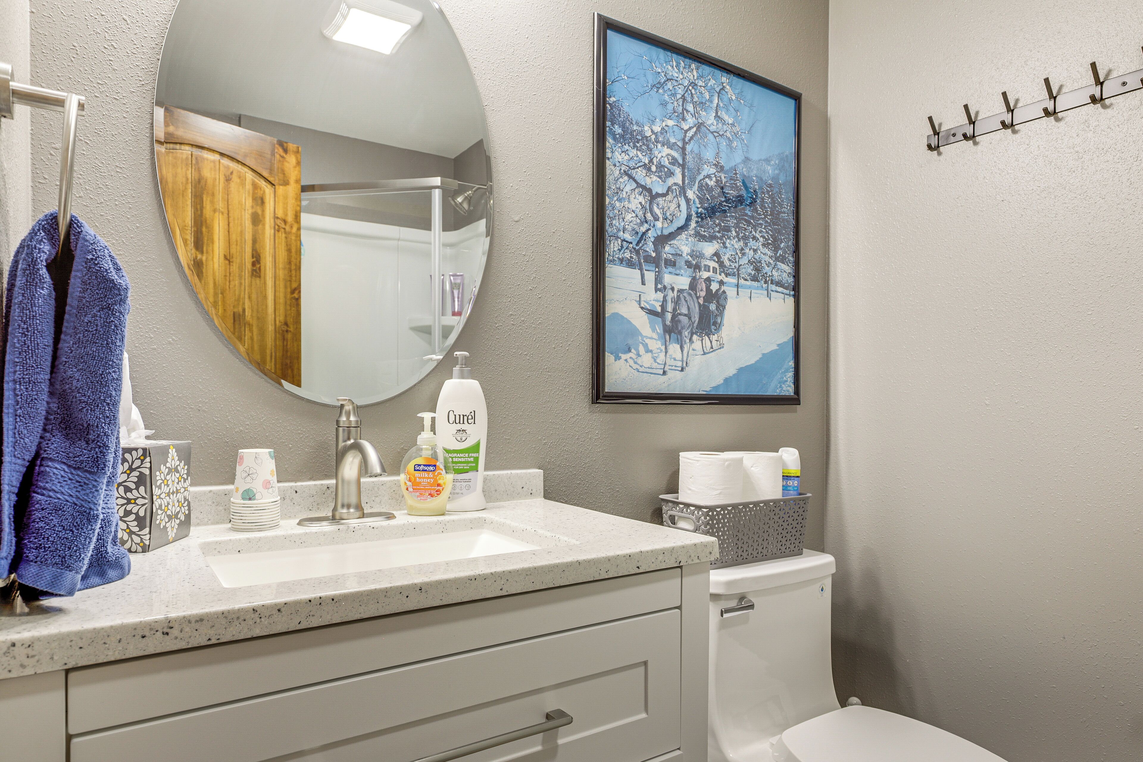 Une salle de bain équipée d’un lavabo, d’un miroir, de toilettes et d’un tableau encadré accroché au mur.