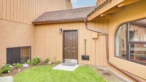 Uma casa com porta marrom, um pequeno jardim frontal e uma janela.